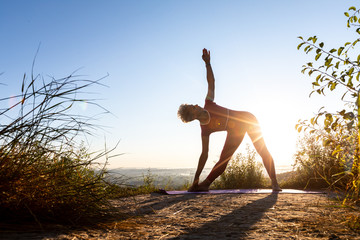 Woman master of zen yoga standing at sunrise near the grass