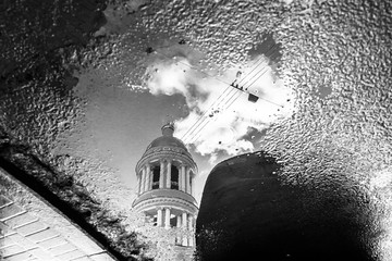 Vintage bell tower of orthodox church reflected in puddle