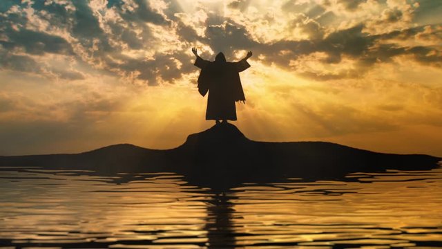 Silhouette of Jesus with open arms on a shore