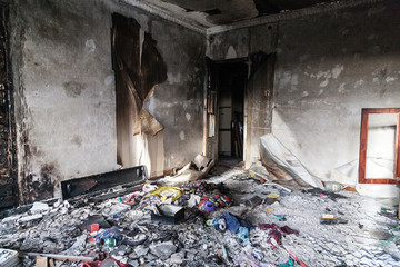 Interior of an abandoned house after a fire with a pile of rubbish on the floor