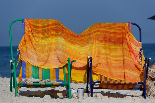 two chairs whit a orange towel at the beach in rio de janeiro