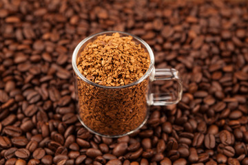Instant, freeze-dried or granulated coffee in a transparent cup on the background of roasted coffee beans. Used to make a cold Dalgon coffee drink. Selective focus