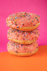 Pink donut with sprinkles on a orange and purple backgroud