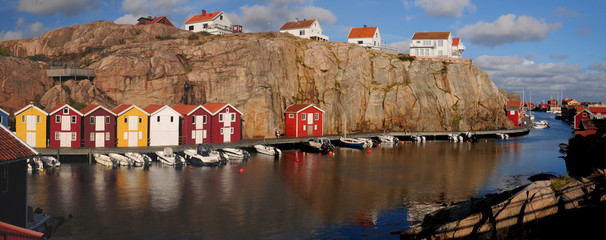 Fototapeta na wymiar Panoramic View To Coloured Boat Houses At Smogenbryggan In Smogen On A Sunny Summer Day With Some Clouds In The Sky