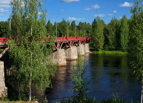 Red Wooden Bridge Lejonstromsbron In Skelleftea On A Sunny Summer Day With A Clear Blue Sky