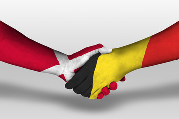 Handshake between belgium and denmark flags painted on hands, illustration with clipping path.