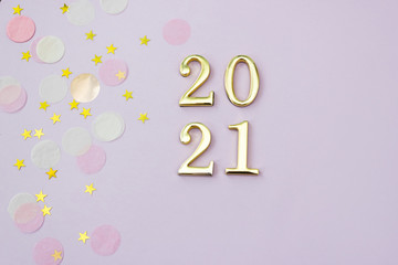2021 numbers on lilac background are decorated with gold and pink confetti. New Year concept. Selective focus.