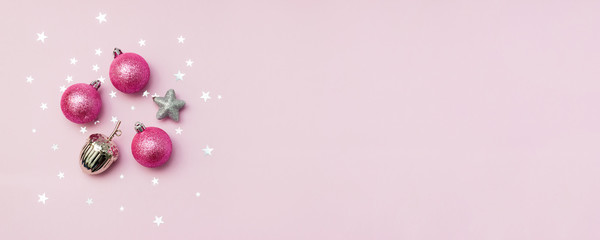 Silver and pink Christmas decorations on pink background with star confetti. New Year concept. Selective focus.