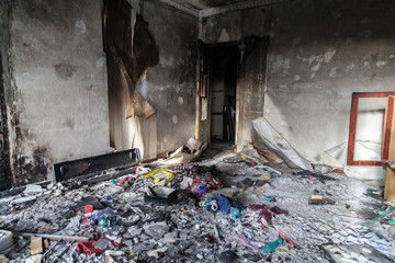 Interior of an abandoned house after a fire with a pile of rubbish on the floor