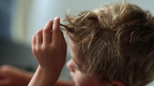 Child playing with hair and snacking. Pensive contemplative toddler boy