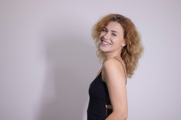 Fototapeta premium emotional portrait of a beautiful curly blonde-redhead in black undershirt. High quality photo