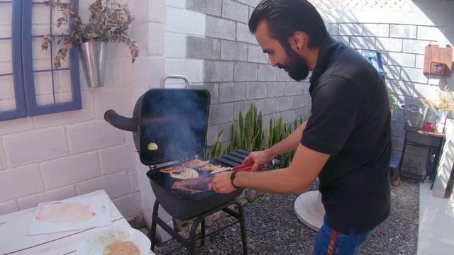 Hombre joven cocinando a carne asada a las brasas en c&aacute;mara lenta 4K
