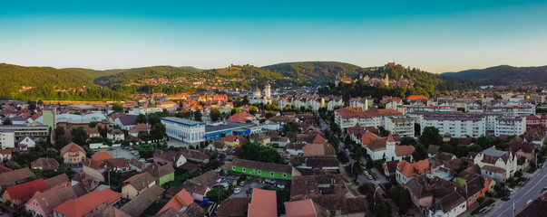 Drone aerial evening panorama of Sighisoara, Romania with Citadel and Biserica din Deal rising...