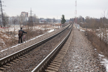 Naklejka premium A man with a bicycle walks along the railway