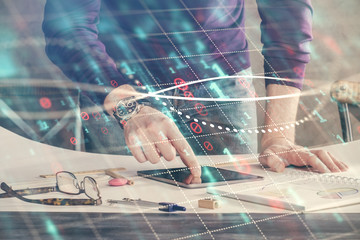 Double exposure of man's hands holding and using a digital device and forex graph drawing. Financial market concept.