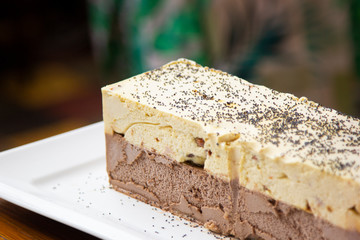 Refreshing cream ice cream with nuts and chocolate, served piece on plate.