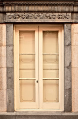 One simple old classic window, closed and surrounded by carved ornamental sandstone architectural datails.