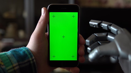 Cyborg uses the phone. Gray mechanical hand swipe down on smartphone with green screen. Chroma key.