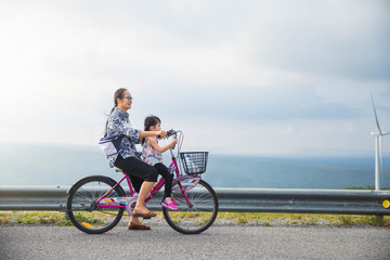 Grandmother with granddaughter in park.  Little Asian girl and grandmother riding on bicycle with great fun. family, leisure and people concept.