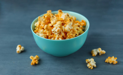 Blue dish filled with popcorn on a gray background. Selective focus. Leisure