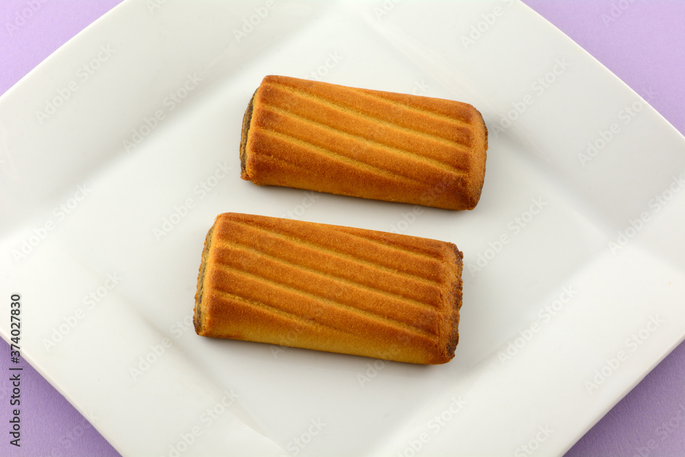 Sticker two biscuit cookies with date filling on white dessert snack plate on lavender background