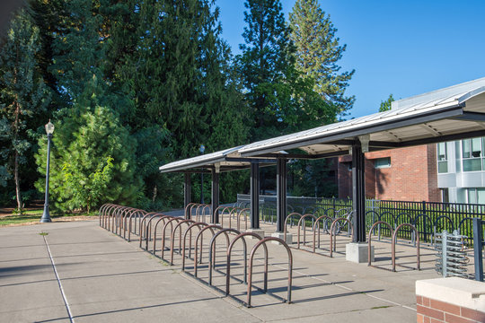 Empty bike racks on a bright, sunny public university campus highlight the absence of students.