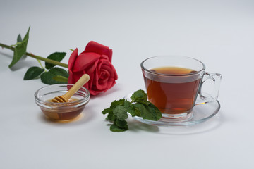 Tea in cup, honey, and mint leaves isolated on white background.