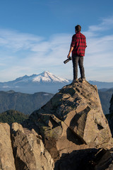 Obraz premium Man Standing On Cliff With Camera In The Pacific Northwest 