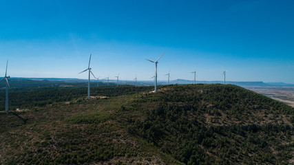 Fototapeta na wymiar Aerial view of Wind Generating stations at big first mountains on a background of blue sky. Spain