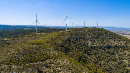 Aerial view of Wind Generating stations at big first mountains on a background of blue sky. Spain