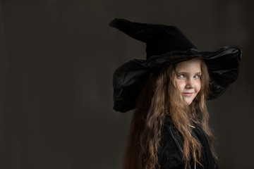 Litlle girl in halloween witch costume on gray background 