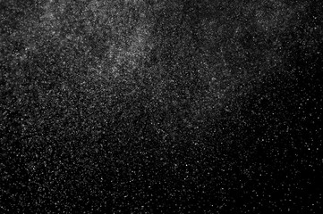 Abstract splashes of water on black background. Freeze motion of white particles. Rain, snow overlay texture.