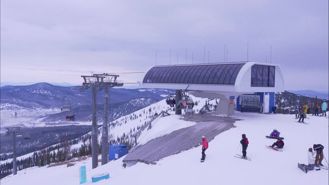 numerous tourists in warm suits walk from poma lift to ride skies and skateboards along snowy hill slope on nice winter day timelapse