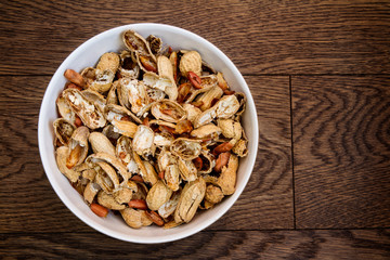 Bowl filled with empty peanut shells; bowl of broken peanut shells with peanuts eaten