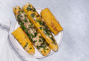 Grilled corn on cob sprinkled with parsley and grated parmesan