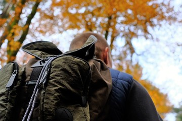Autumn walks and travel. A traveler close-up with a backpack  in the autumn forest. Sports and hiking in the fall season.Autumn  nature landscape. Fall season