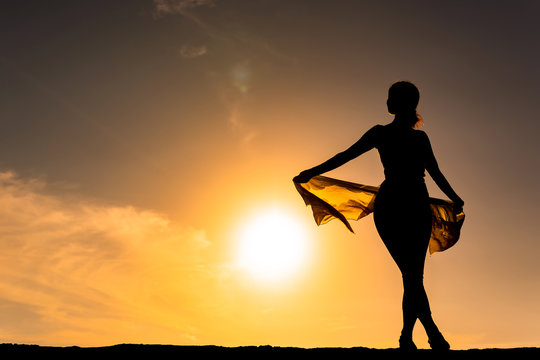 太陽を背景に立つ女性のシルエット