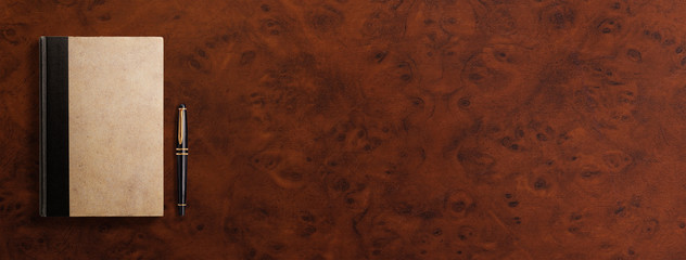 茶色いマホガニーのテーブル上にある、古いノートと万年筆 。 書評、日記のイメージ