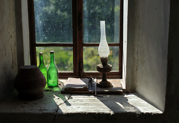 Still life with an old kerosene lamp on the window in a village house.