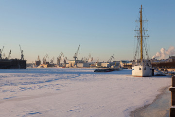 A white sailboat in the winter parking is frozen into the ice. Training ship. Saint Petersburg