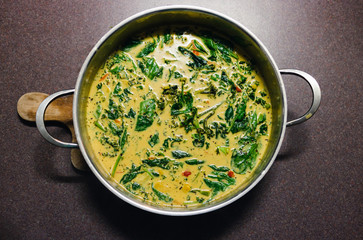 plant-based food,  vegan green curry with spinach broccolini kale and stir fry vegetables in the pan