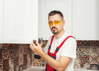 Maintenance worker installing new furniture with screwdriver and look at camera