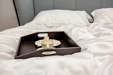 Tray with coffee in a large bed in the morning on a bed linen