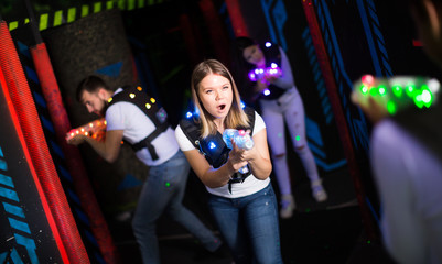 Portrait of girl with laser gun having fun on dark lasertag arena