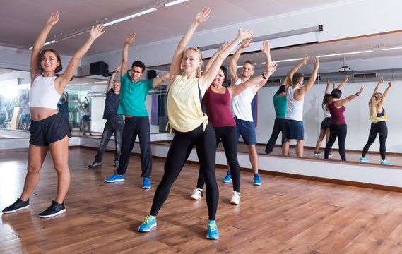 Laughing positive people learning zumba steps in dance hall