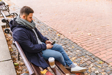man drinking coffee outdoors autumn season talking on the phone