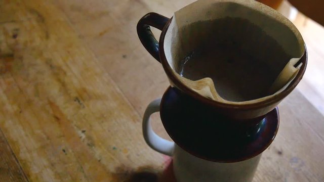 Closeup image of pouring hot water to make a drip coffee on vintage wooden table