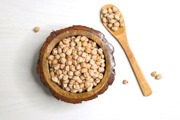 Uncooked dried Chickpeas in a wooden bowl on white background. Preparation for making a hummus dish.High protein ingredient with copy space.  
