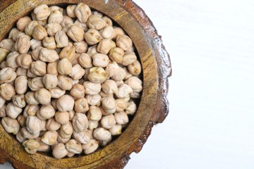 Uncooked dried Chickpeas in a wooden bowl on white background. Preparation for making a hummus dish.High protein ingredient with copy space.  