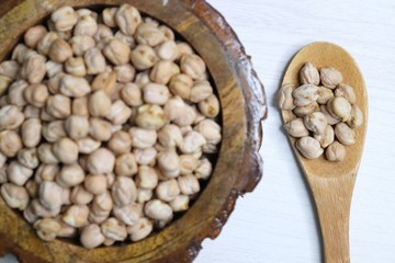Uncooked dried Chickpeas in a wooden bowl on white background. Preparation for making a hummus...